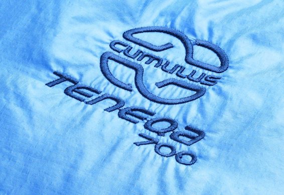 Logo péřového spacáku Cumulus Teneqa 700 ve světlé modré barvě.